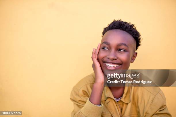 portrait of a smiling young woman wearing yellow jacket in front of yellow wall - candid stock pictures, royalty-free photos & images