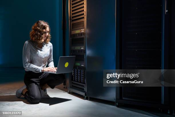 young female it engineer using laptop when working with supercomputer - supercomputer stock pictures, royalty-free photos & images