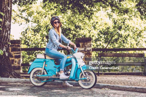 smiling woman on motor scooter stopping on the side of the road - vintage motorcycle helmet stock pictures, royalty-free photos & images