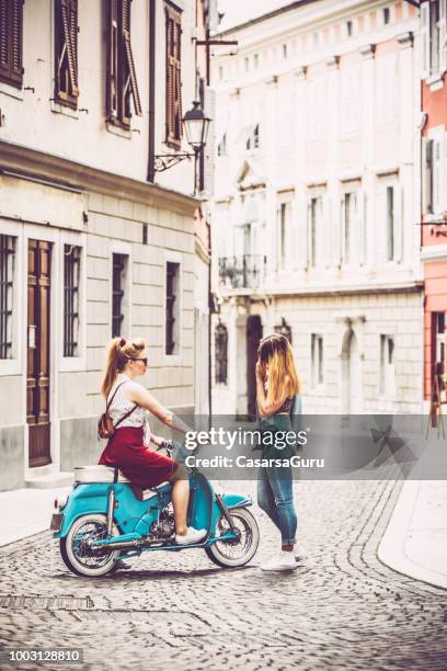 junge frauen treffen auf stadtstraße und reden - moped stock-fotos und bilder