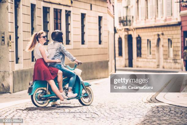 junge lesben paar altmodische motorroller auf italienischen straßen fahren - roller vintage stock-fotos und bilder