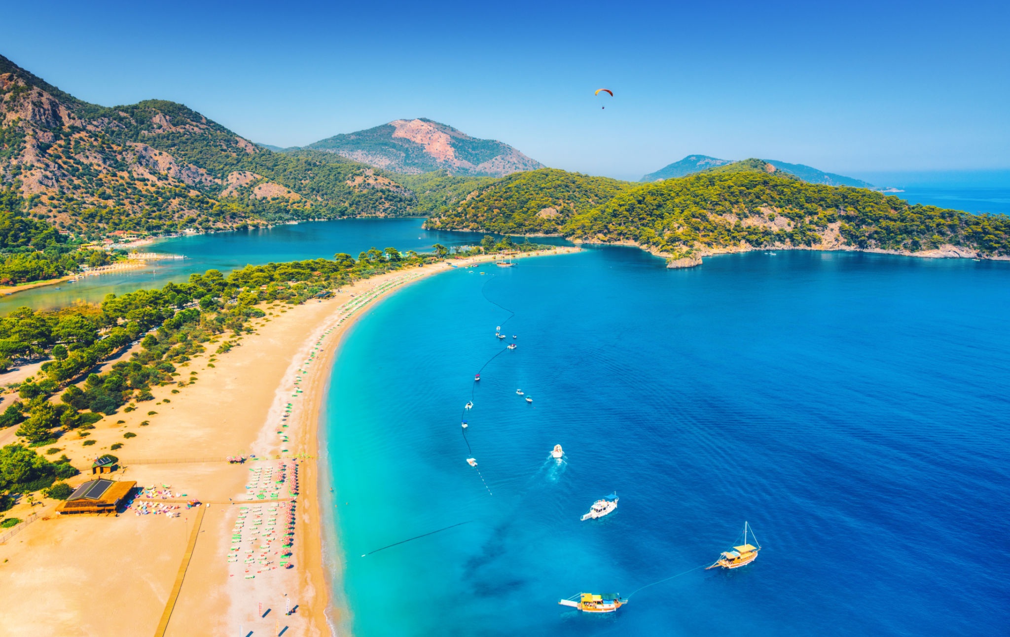 Amazing aerial view of Blue Lagoon in Oludeniz, Turkey. Summer landscape with sea spit, boats and yachts, green trees, azure water, sandy beach in sunny day. Travel. Top view of national park. Nature Amazing aerial view of Blue Lagoon in Oludeniz, Turkey. Summer landscape with sea spit, boats and yachts, green trees, azure water, sandy beach in sunny day. Travel. Top view of national park. Nature