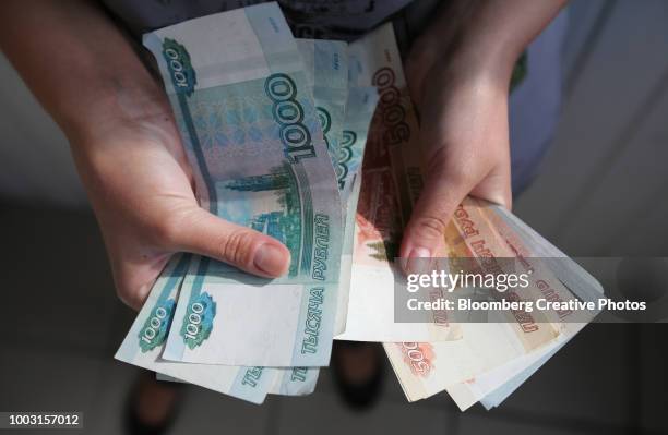 an employee holds 1000 and 500 ruble banknotes - billete de rublo ruso fotografías e imágenes de stock