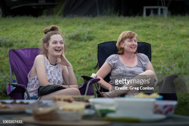 mother and daughter sitting in camping chairs, smiling in conversation - camping new south wales stock pictures, royalty-free photos & images