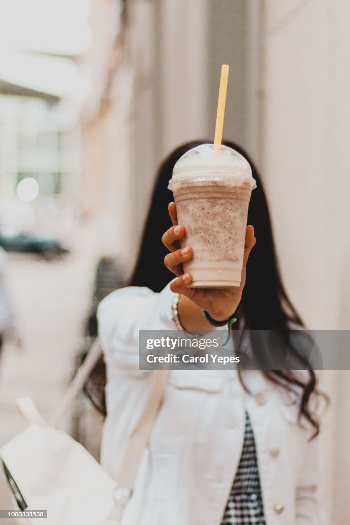 Woman holding coffee milkshake at the street