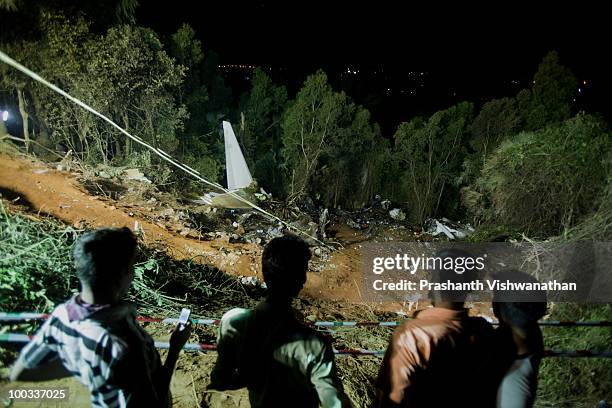 Onlookers look on at the airline crash site May 22, 2010 in Mangalore, India. An Air India Express Boeing 737-800 series aircraft arriving from...