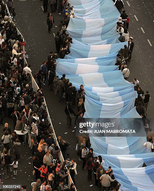 People hold part of a huge Argentine flag along 9 de Julio avenue, in Buenos Aires on May 22, 2010 as part of the celebrations for the Bicentenary of...