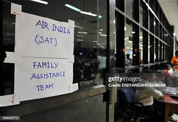 Employees of Air India work at a booth assist family members of passengers on an Air India Boeing 737-800 aircraft which crashed upon landing in...