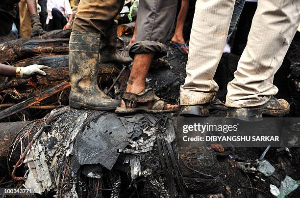Rescue personnel and volunteers walk over wreckage at the crash site of an Air India Boeing 737-800 aircraft which crashed upon landing in Mangalore...