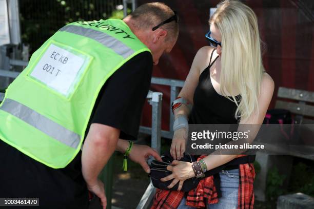 An employee of a security agency checks the belly bumbag of a visitor of Rock im Park at the entrance controls in front of the festival grounds in...