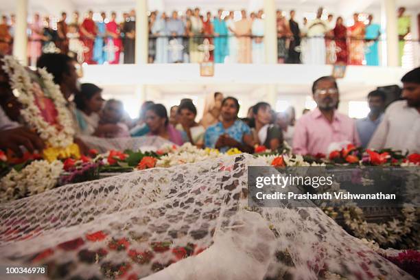 Crucifix is placed in the hand of Air India Express crash victim H. Goldine as her family mourns during a funeral service at the St. Alphonsa...