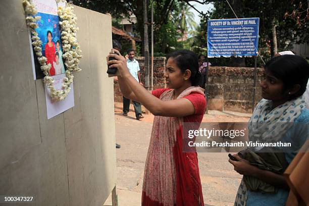 Visitor photographs a picture H.Rosaline and her two daughters H.Goldine and H.Gloria, victims of the Air India Express plane crash, during their...