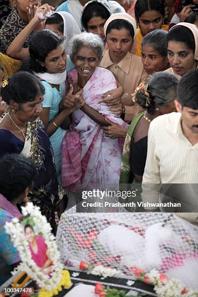 The grand mother of an Air India Express crash victim mourns over the coffins of her daughter and grand daughters, at the St. Alphonsa Catholic...