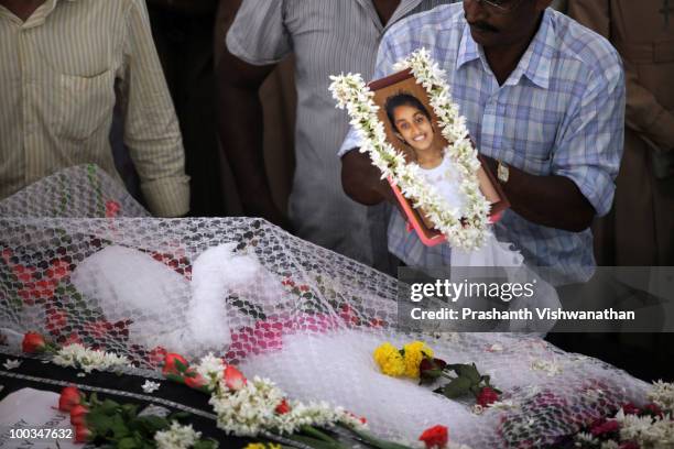 Relative places a photo of H.Gloria, an Air India Express crash victim, onto her coffin during her funeral service, at the St. Alphonsa Catholic...