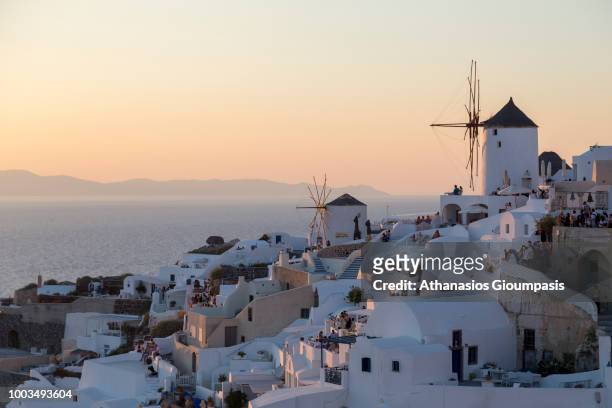 Traditional Windmill during the sun set at Oia caldera with wonderful views to the sea caldera and volcano on July 16, 2018 in Santorini, Greece.