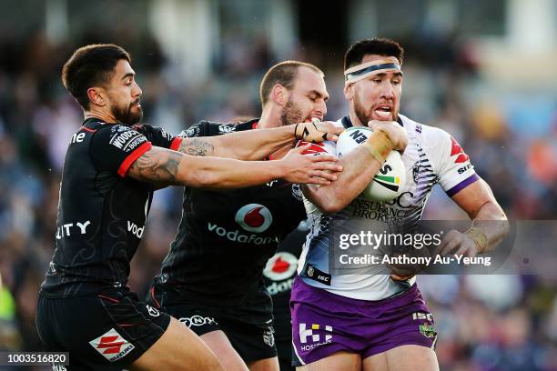 Nelson Asofa-Solomona of the Storm is tackled by Shaun Johnson and Simon Mannering of the Warriors during the round 19 NRL match between the New...