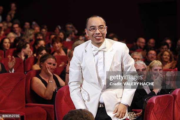 Thai director Apichatpong Weerasethakul stands up after he received the Palm d�Or award for his film "Lung Boonmee Raluek Chat" during the closing...