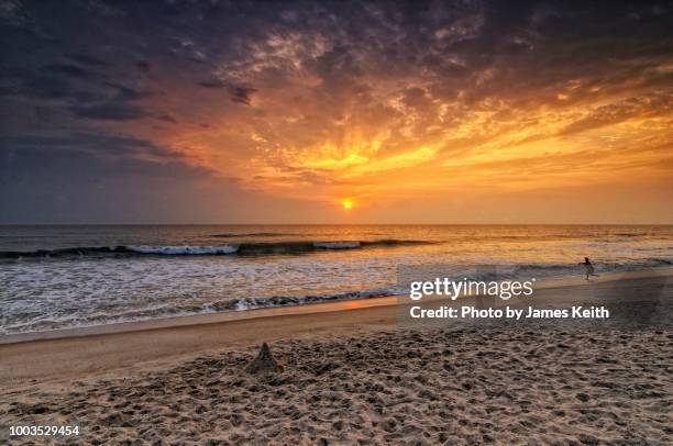 a lone surf fisherman casts into the sea amid a colorful sunrise on playalinda beach, canaveral national seashore. - titusville florida fotografías e imágenes de stock