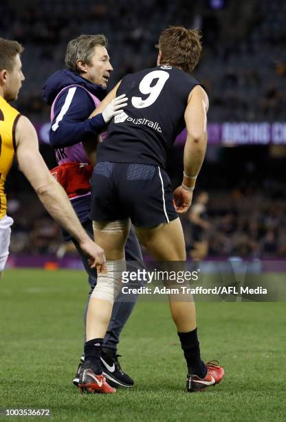 Patrick Cripps of the Blues is checked on by the club doctor after a hit from Daniel Howe of the Hawks during the 2018 AFL round 18 match between the...