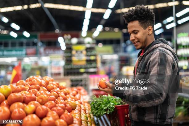 customer choosing tomatoes at supermarket - man buying groceries stock pictures, royalty-free photos & images