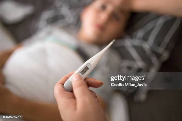 mother checking her sick sons temperature - fever thermometer stock pictures, royalty-free photos & images