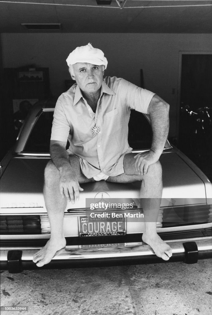 Actor Rod Steiger seated on trunk of his Mercedes with license plate "Courage" in Malibu July 15 1979