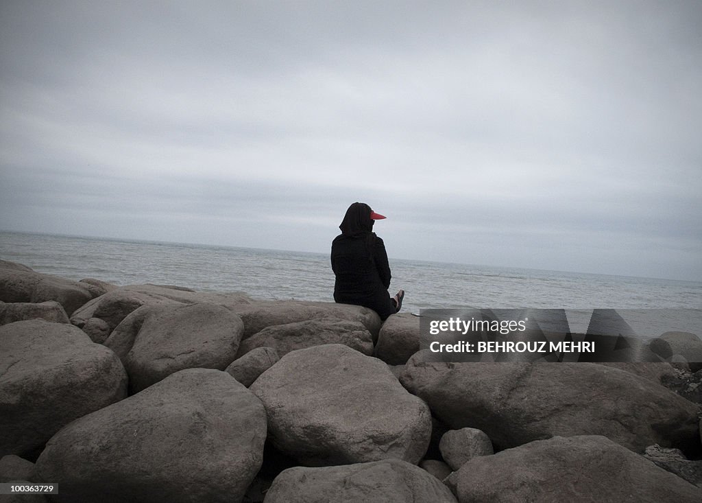 An Iranian woman sits by the water in th