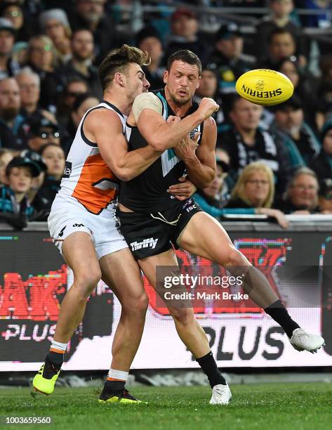 Travis Boak captain of Port Adelaide handballs under pressure from Dylan Shiel of the Giants during the round 18 AFL match between the Port Adelaide...