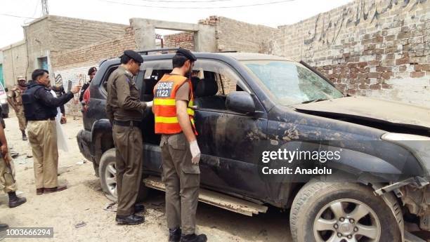 Rescue 1122 members and police officers inspect a damaged vehicle after a suicide bomber blew himself up near the vehicle of Ikramullah Gandapur in...