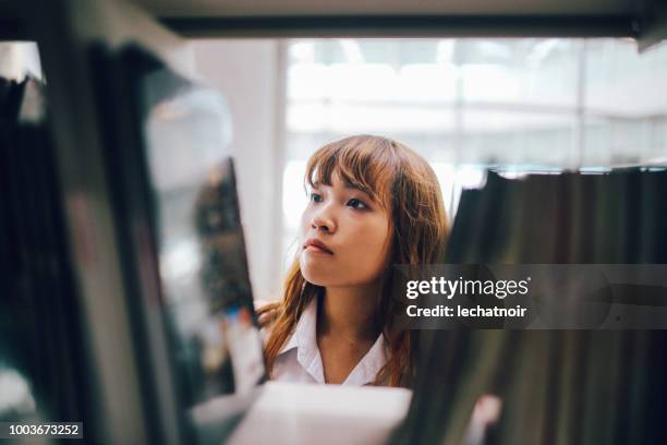 jonge aziatische student op zoek naar boeken in de campusbibliotheek - teenager learning child to read stockfoto's en -beelden