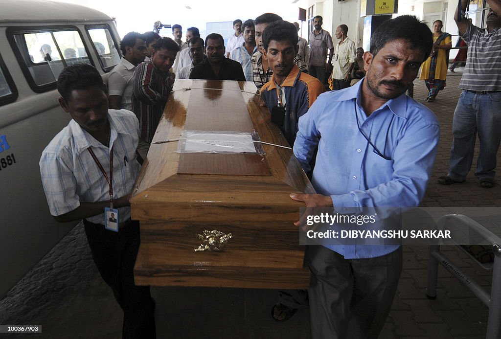 Airport workers carry a coffin bearing t