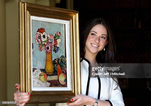 Caitlin Cruckshanks from Lyon & Turnbull holds a still life by Scottish Colourist George Leslie Hunter called Still Life with Fruit and Anemones at...