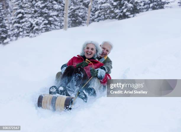 caucasian couple sledding down hill - mature woman winter stock-fotos und bilder