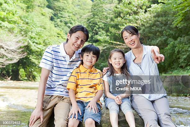 family sitting on rock - front view portrait of four children sitting on rock stock pictures, royalty-free photos & images