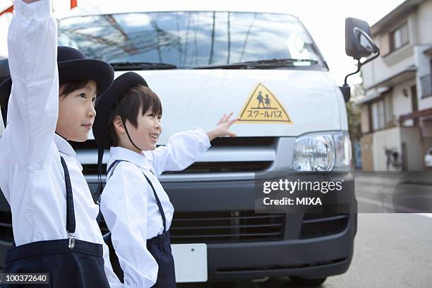 kindergarten children holding up hands in front of school bus - bus front ストックフォトと画像