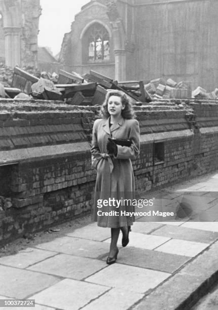 Rosemary Davidson walks home past a bomb-damaged church in Fulham, London, April 1942. Earlier in the day, she had played the role of Britannia in a...