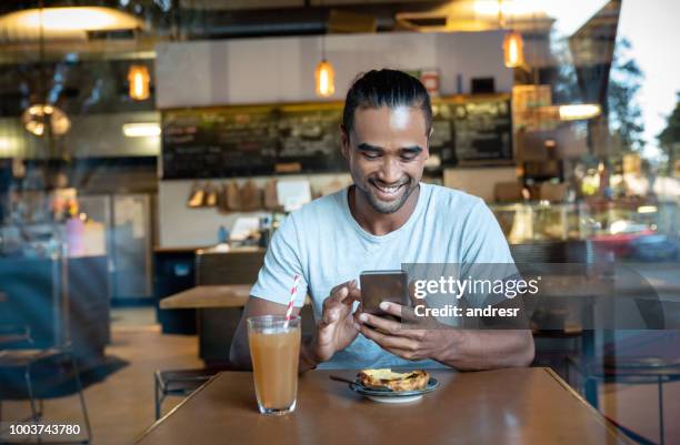 young man texting on his cell phone at a cafe - australian cafe stock pictures, royalty-free photos & images