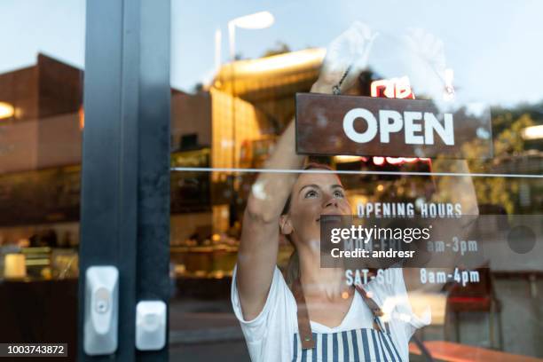 propietario de negocio feliz colgando un signo abierto en un café - abriendo tienda fotografías e imágenes de stock