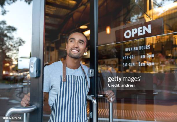 happy waiter opening on the doors at a cafe - open stock pictures, royalty-free photos & images