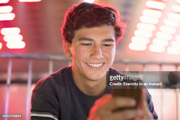 young teenage boy texting at a fair at night - i love teen boys stock pictures, royalty-free photos & images
