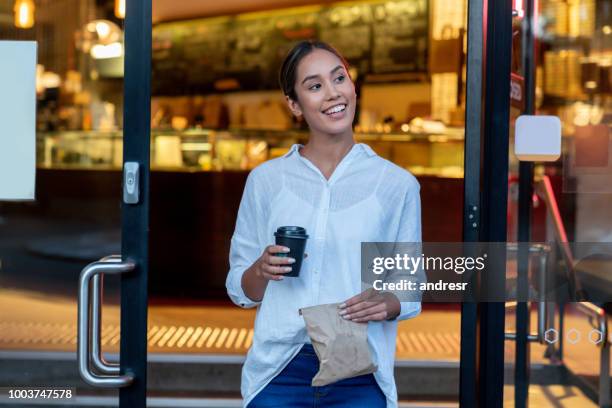 woman exiting a cafe carrying coffee to go - leaving restaurant stock pictures, royalty-free photos & images