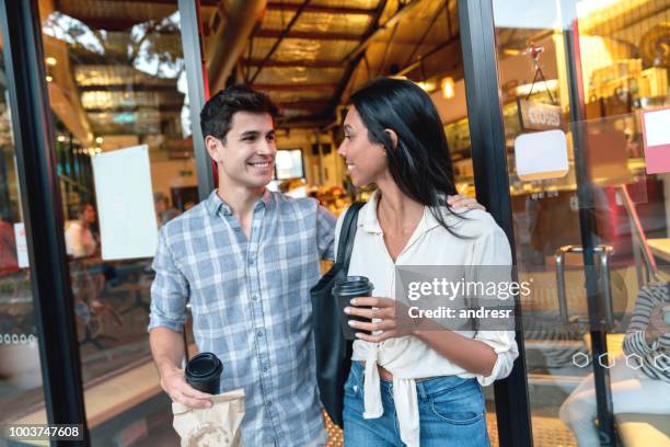 couple exiting a cafe carrying coffee to go - leaving store stock pictures, royalty-free photos & images