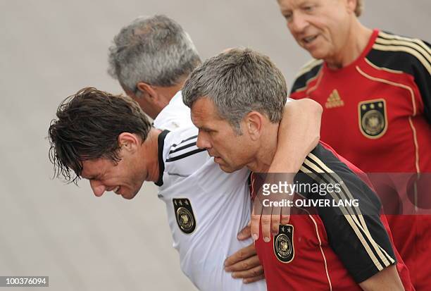 Germany's midfielder Christian Traesch is walked out of the training center by team medics after sustaining a foot injury during a training match...