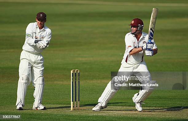 Mal Loye of Northamptonshire hits the ball towards the boundary, as Steve Davies of Surrey looks on during the LV County Championship match between...