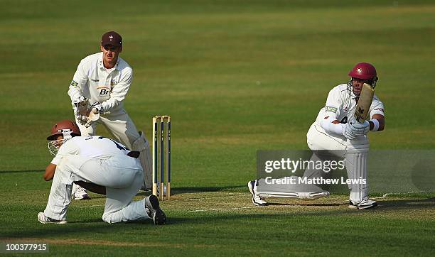 Nicky Boje of Northamptonshire hits the ball towards the boundary, as Steve Davies and Arun Harinath of Surrey looks on during the LV County...