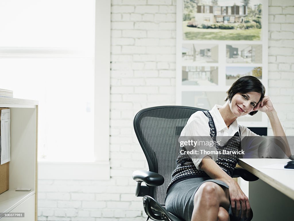 Businesswoman seated at desk in office smiling