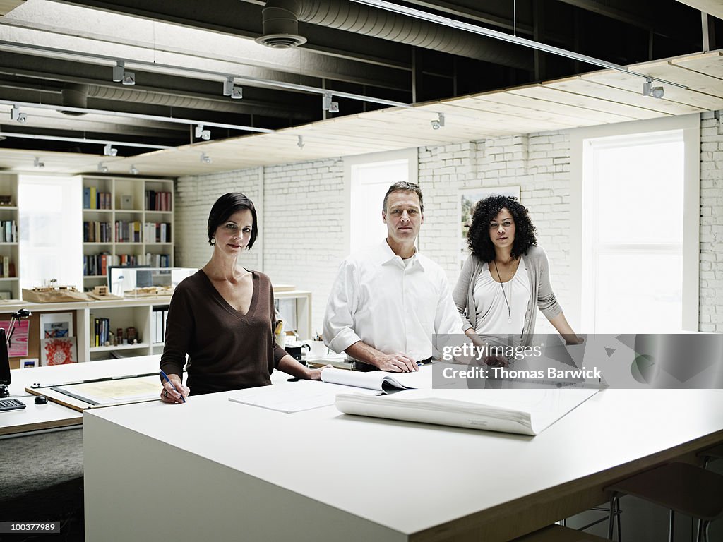 Three architects standing at desk with plans