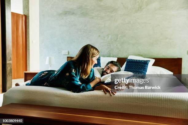 smiling couple relaxing on bed at luxury hotel - couple in bed fotografías e imágenes de stock