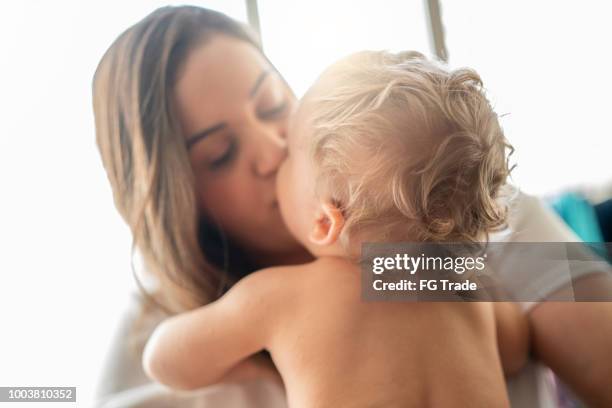 madre besando a su pequeño bebé lindo en casa - beso en la boca fotografías e imágenes de stock