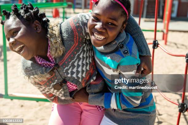 due gemelle afro-americane che giocano nel parco giochi della scuola durante la pausa.. - ragazza scuola foto e immagini stock